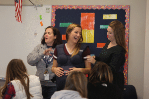 Family and Consumer Sciences teacher Eileen Gray and senior Eileen Marti assist senior Katylyn Seyb with putting on an empathy belly.