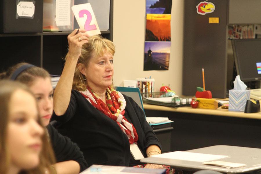 Debate teacher 
Jeanette Hardesty holds up a time card while her students practice for their  meet at Olathe North High School on Saturday, Oct. 26. 
Photo by Halie Rust