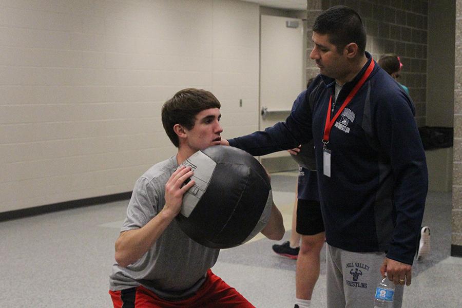 Motivating senior Bobby Hellon, fitness teacher Travis Keal leads a medicine ball workout during a lifetime fitness class on Monday, Nov. 11. Keal was recently nominated as the October Teacher of the Month due to his inspiring words and support for his students.