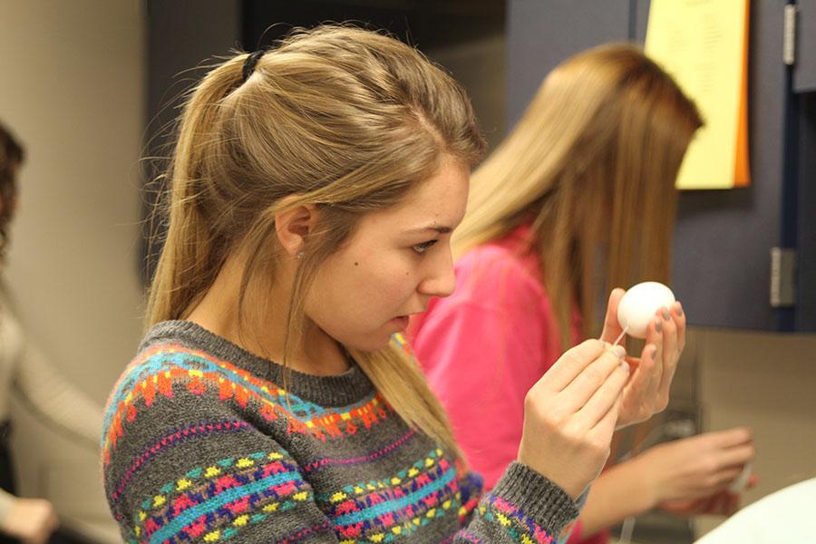 Making her egg baby for the class family studies, freshman Emma Mantel drains the yolk from the egg on Wednesday Dec. 4. 