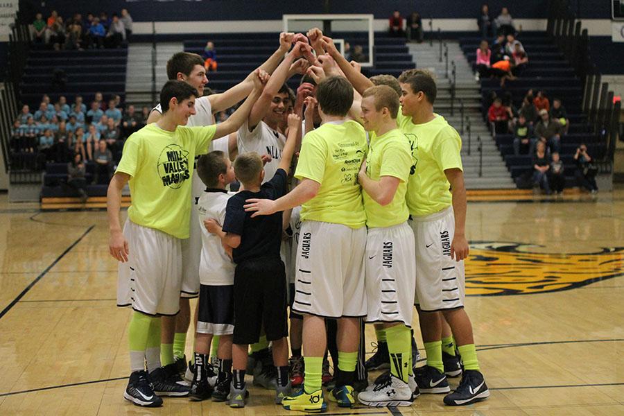 Huddling before a basketball game against Olathe Northwest, junior Mitch Perkins and his teammates get pumped up and prepare to play on Saturday, Feb. 15.