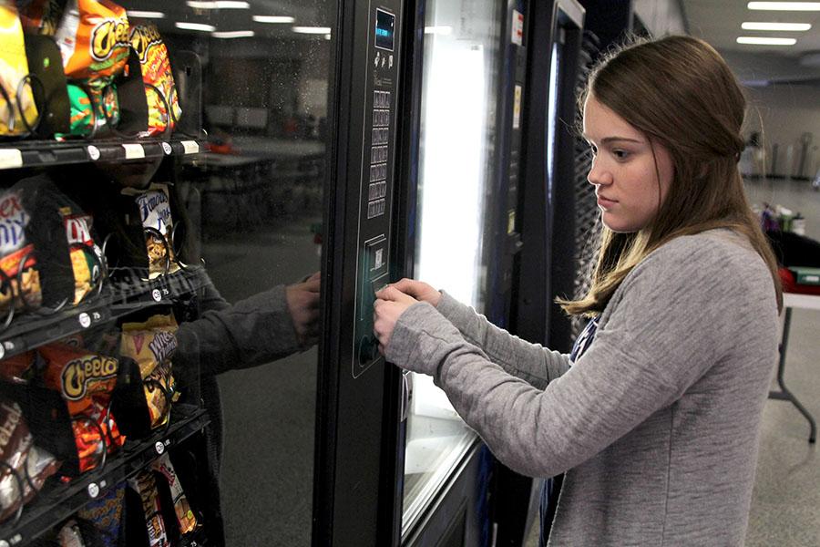 Dollar in hand, sophomore Catherine Westin looks over her options at the vending machine on Thursday, Feb. 13. Next year, vending machines will have to meet the incoming nutritional standards. I think the changes will push students to make healthier choices while at school, Westin said.