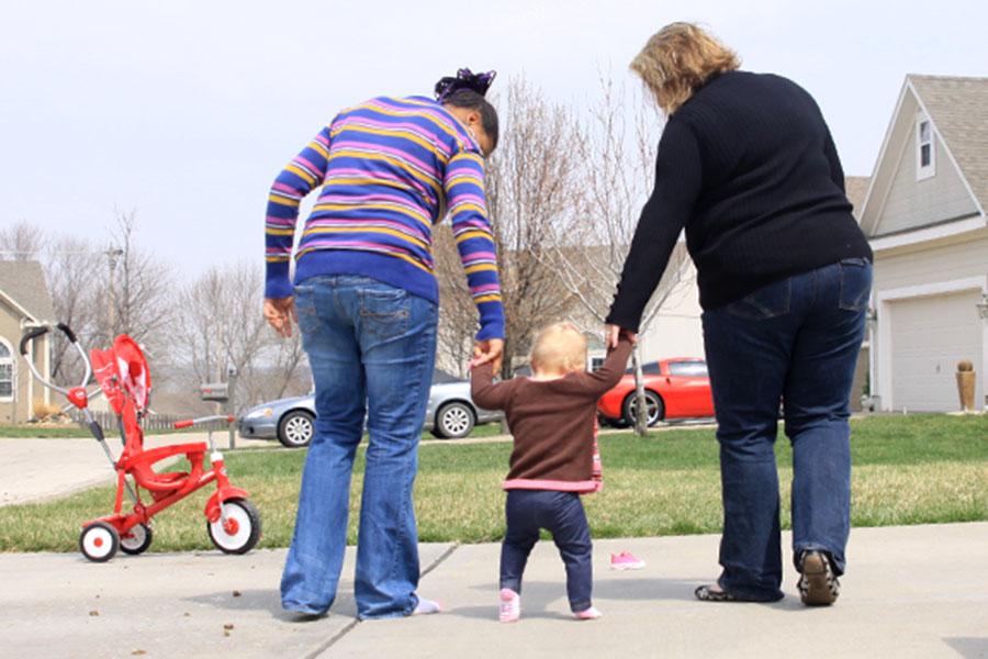 Sophomore Sydney Humphrey and her mom help her foster sister walk across the driveway on Sunday, April 6. I like having her around the house, Humphrey said. [It is fun] watching her grow up even though she is a handful. 