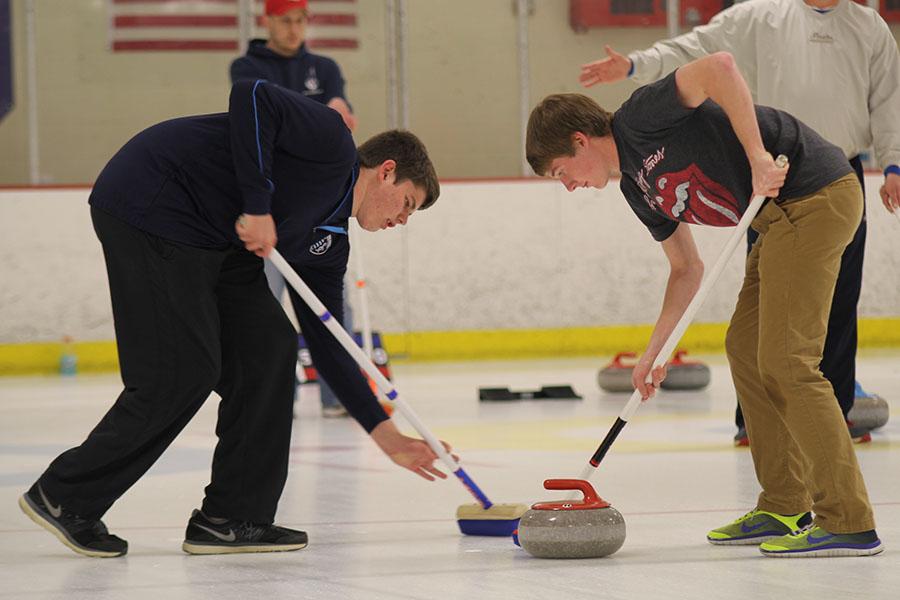 Sweeping the path of the stone, freshmen Austin Snyder and Nick Nelson attempt to knock off the other opponents stone on Saturday, April 5.