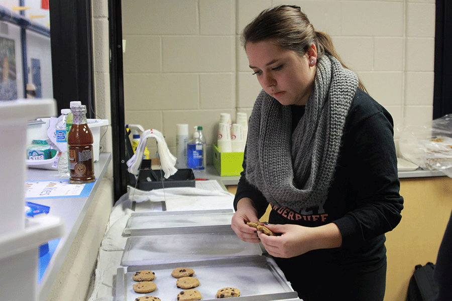Placing cookies on trays on Thursday, Dec. 4, senior Lindsay Stockham prepares for the launch of the new cookies added to the Caddy Shack. 
