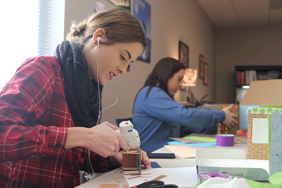 Senior Ashley Vest glues together parts of her Teaching as a Career mini classroom on Monday, Dec. 8. 