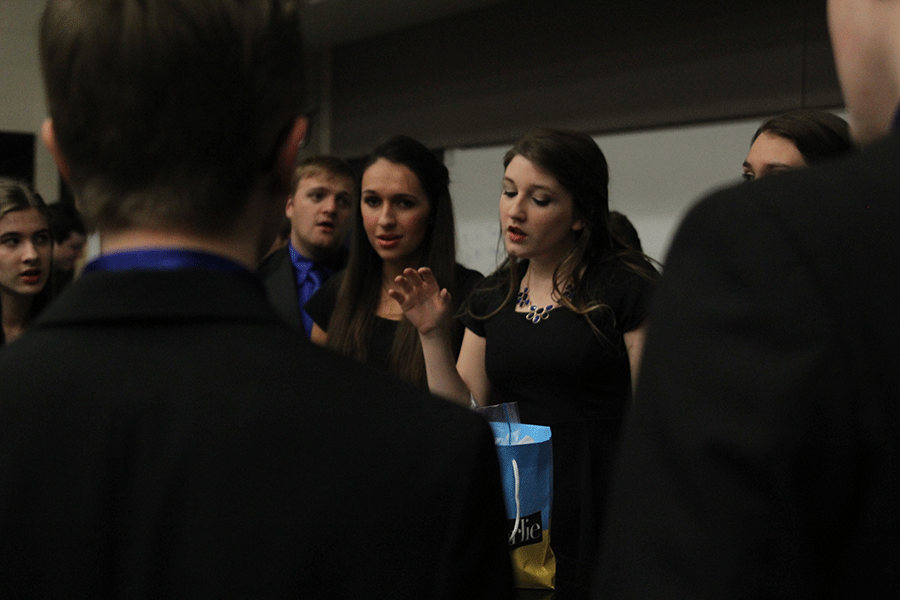 While rehearsing backstage for the choir concert on Thursday, Dec. 4, senior Brienna Kendall directs a group of singers.