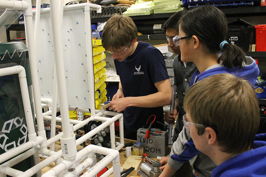 Working with the robotics engineering team on Tuesday, Jan. 27, senior Kyal Long attaches the electrical box onto the chassis.