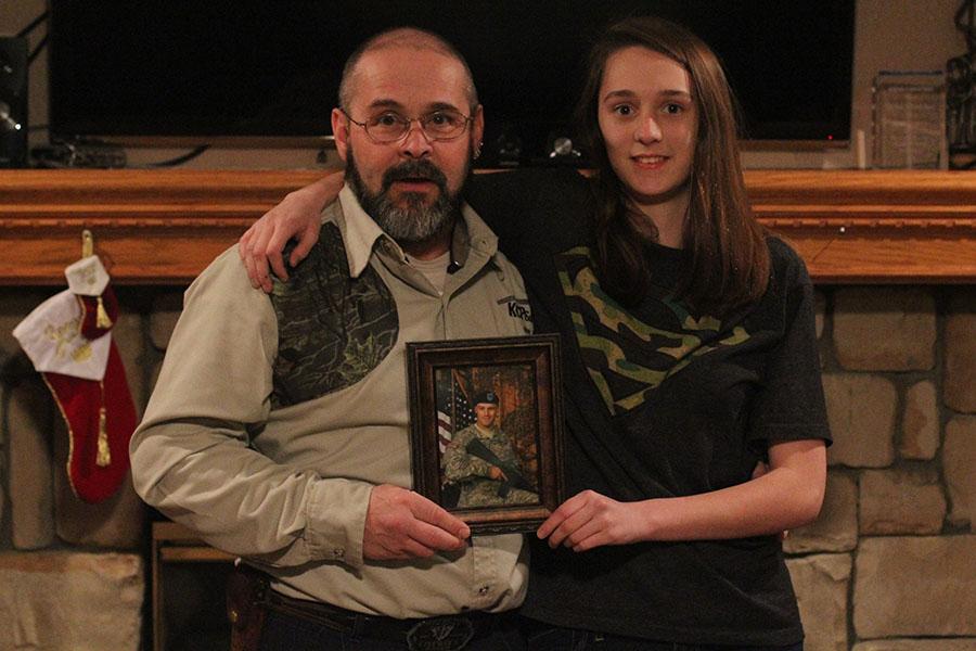 Standing with her father Martin Torson, sophomore Stacia Torson holds a photo of her brother Andrew Torson who is currently serving. 