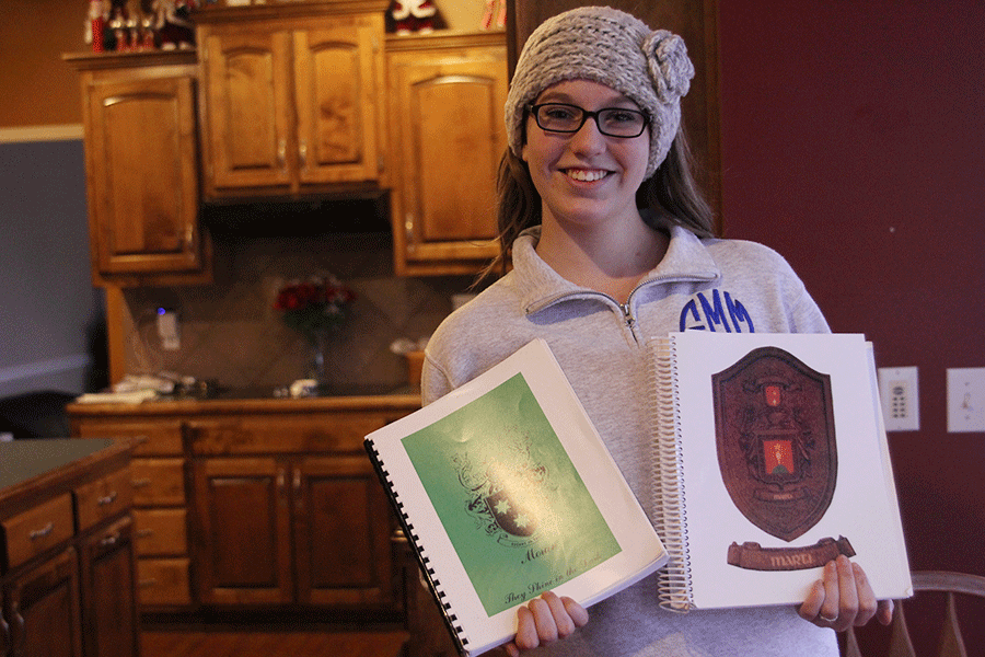 Junior Eileen Marti holds books with information tracing back her family history on Wednesday, Dec. 17.