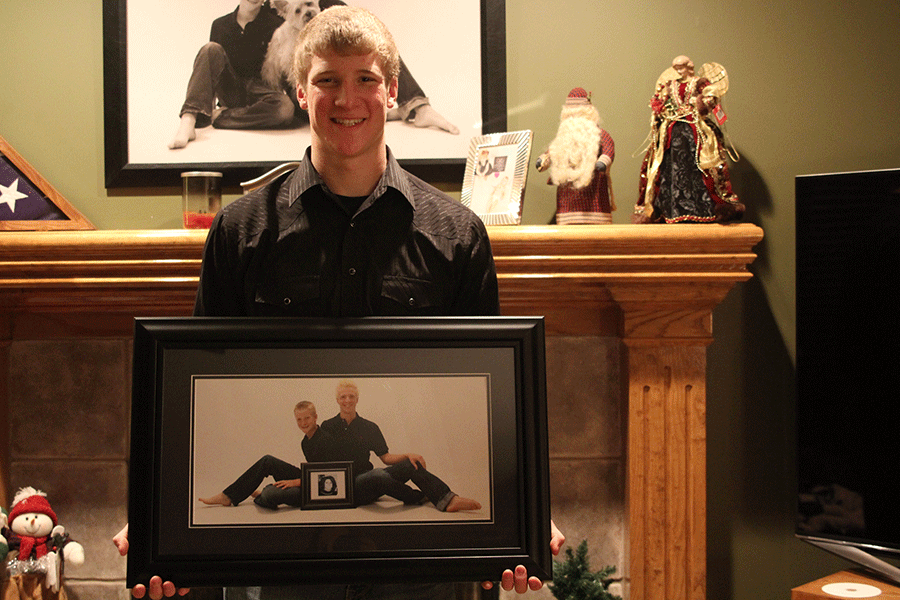 Junior Cole Morris holds a picture of him and his brother along with a picture in remembrance of his mother on Monday, Jan. 12.  