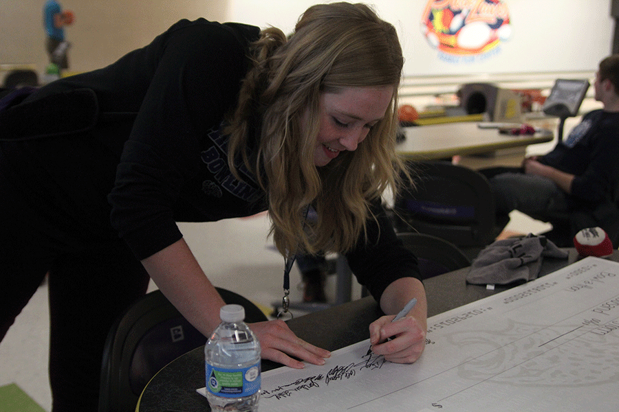 Junior Isabel Crain signs the check for the special olympics team, Shawnee Storm.