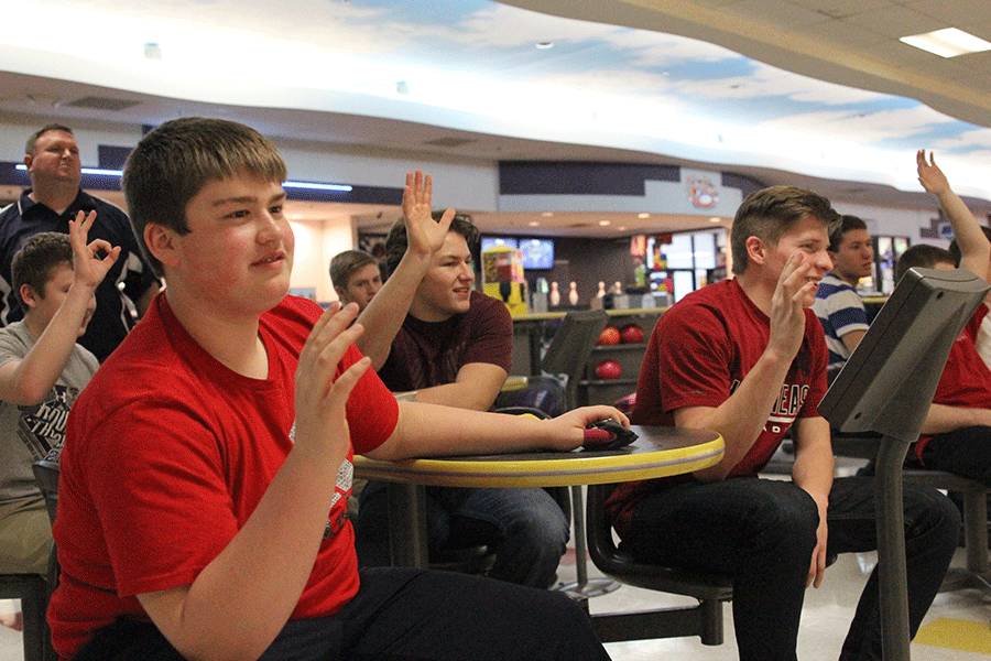 Sophomore Jesse Bowden and Junior Brock Miles raise  their hands as a good luck charm to one of their teammates getting ready to bowl.