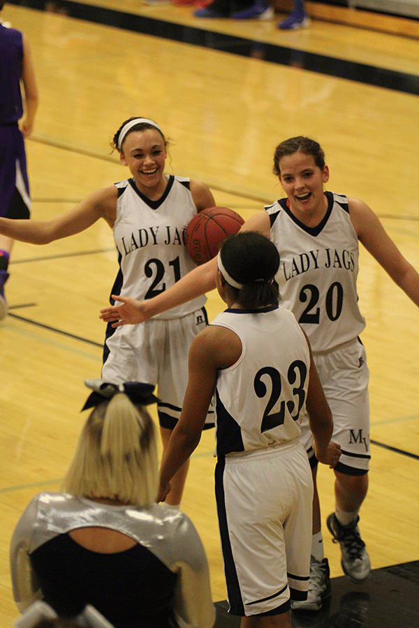 Seniors Whitney Haslett and Lexie Myers give high-fives to teammate Jabria Leggett.