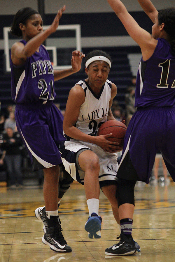 Advancing through two opposing players, senior Jabria Leggett goes for a shot against Piper on Friday, Feb. 20. 