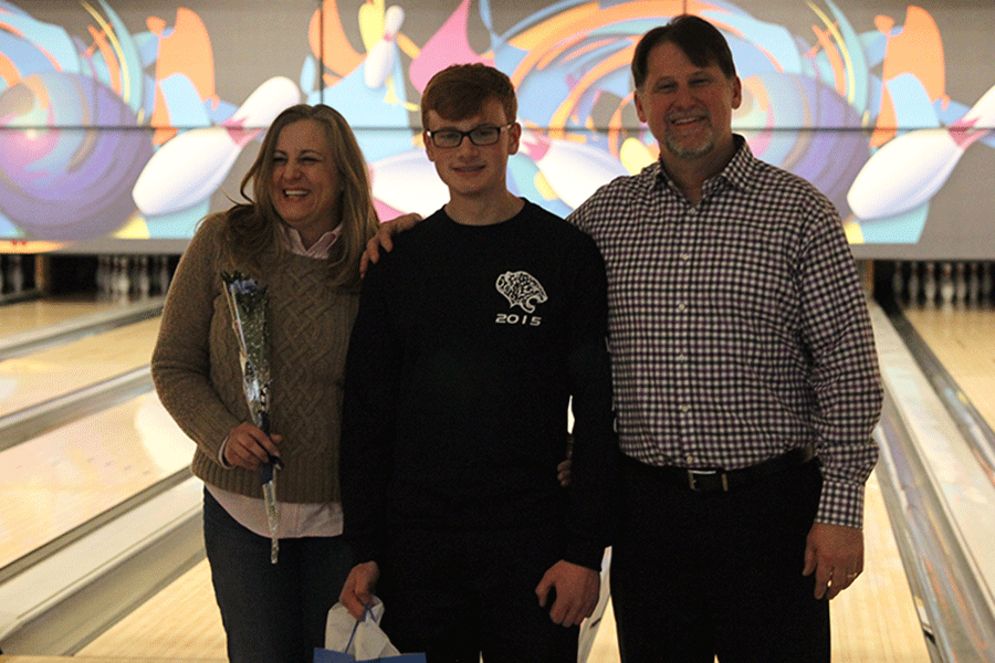 Senior Nick Cain stands with his parents while holding his gift from the team.