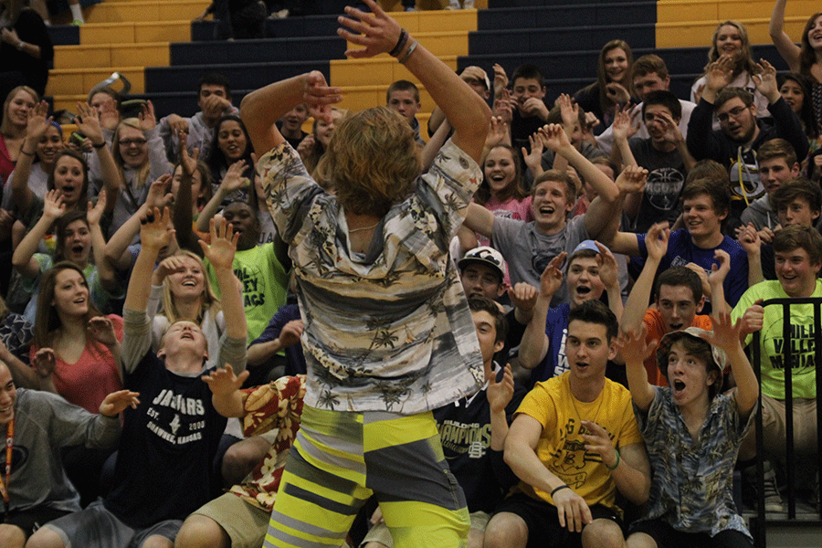 Dressed in his Hawaiian attire, junior Lucas Krull leads the student section in the roller coaster at halftime.