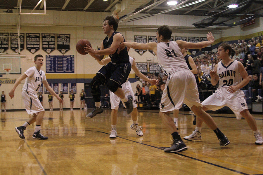 Passing the ball, junior Logan Koch desperately avoids Aquinas defense.