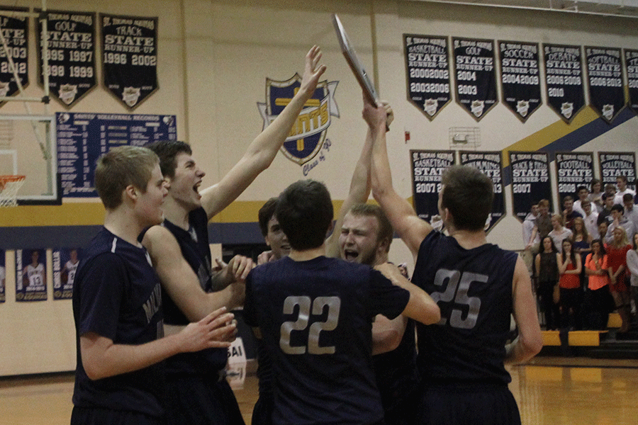 The boys basketball team holds its sub-state championship trophy after its victory over St. Thomas Aquinas.