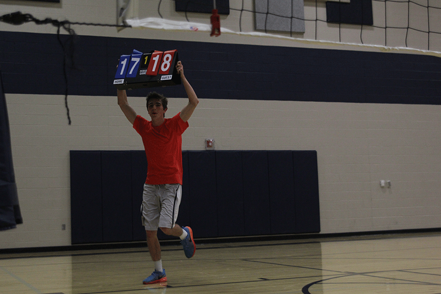 Junior Ethan Lane runs with the scoreboard after his teams first victory of the night on Wednesday, March 25. 