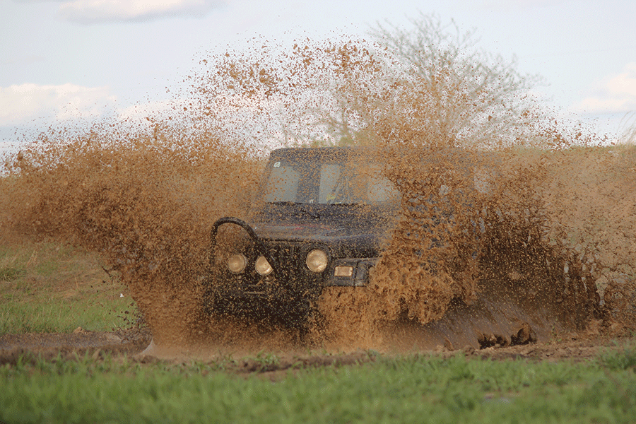 In his 1998 Jeep Wrangler, junior Mitch Cowan speeds through a pool of mud and water on Monday, April 20.