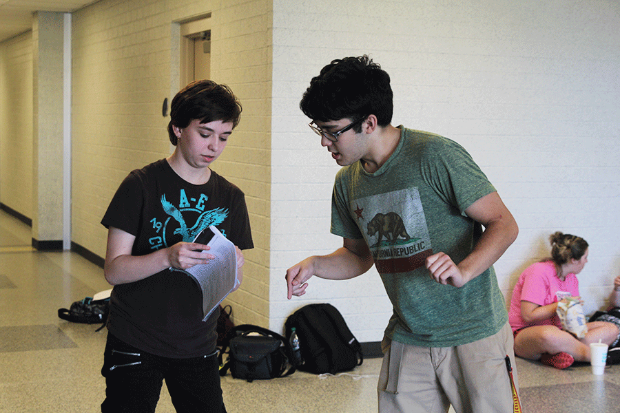 Helping junior Sohail Ibrahimi with his lines, junior Bethany Coleman reads them aloud for him in the hallways on Wednesday, April 1. “Getting to see the whole [play] grow is awesome,” Coleman said. “I help make the characters better [by] making suggestions and helping them with their lines.”
