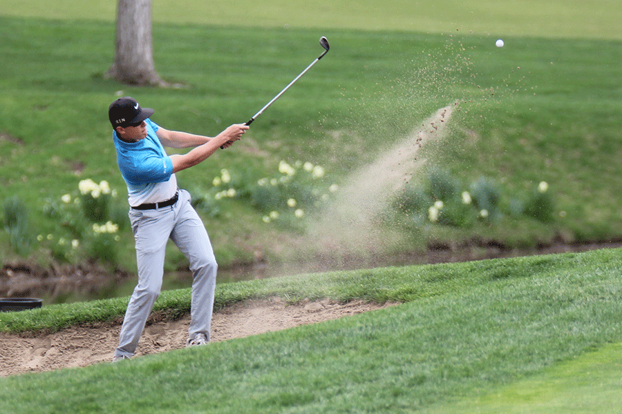 In the bunker, senior Ben Hadden swings to propel the ball out of the sand trap.