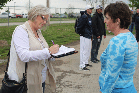 At a De Soto High School baseball game, district resident Julianne Wright collects a recall petition signature from another resident on Friday, April 24.