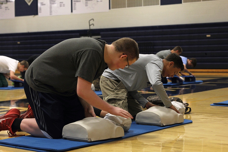 Freshman Cameron Mitchell pats the mannequin to simulate the steps of CPR.