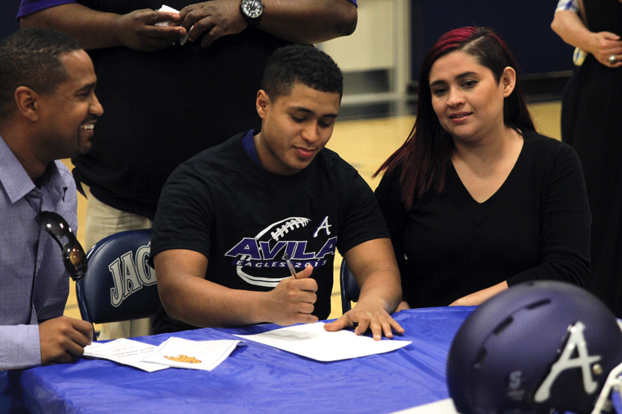 Following+the+ceremony%2C+senior+Isaiah+Young+pretends+to+sign+as+he+takes+a+picture+with+his+family.