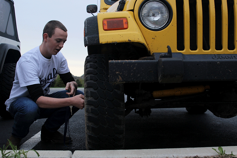 Junior Logan Schmidt takes air out of his Jeep’s tires after checking the air pressure on Monday, April 13. 
