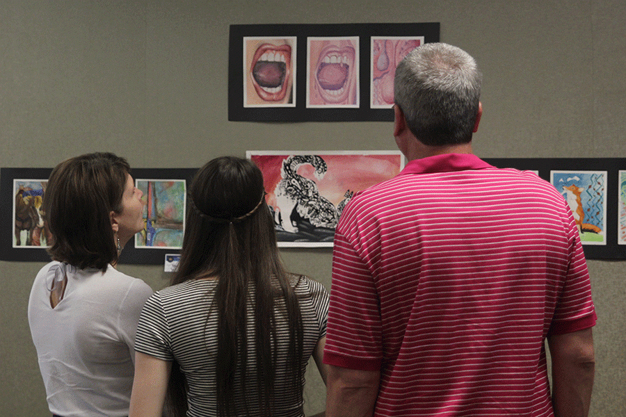 Junior Abbie Hughes views art from students featured at the Country Club Bank on Wednesday, May 6.