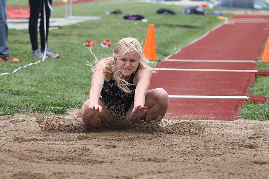 Reaching forward, senior Holly Webb lands in the sand on Friday, May 8.