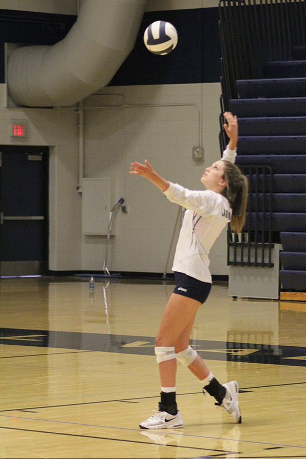 In preparation to spike the ball, senior Maddie Little throws the ball in the air on Thursday, Oct. 16 in the gymnasium. “I’ve learned so much about teamwork and hard work and selflessness,” Little said. “High school volleyball has taught me to never take advantage of what you are given.” 