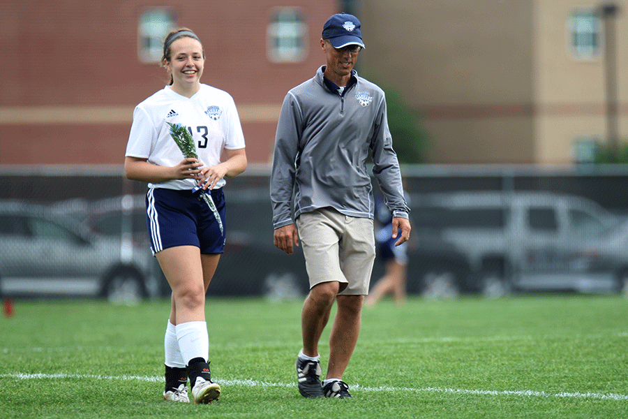 Before the start of the game vs. Blue Valley North on Monday, May 5, senior Sara Hopkins walks onto the field with head coach Arlan Vomhof for senior night presentations. The game ended in a 1-1 draw after lightning forced it to end early into the second half.