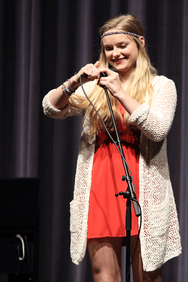 Senior Libbey DeWitte adjusts the microphone stand before performing in the senior showcase.