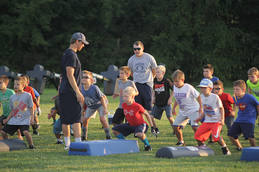 Children learn how to safely prepare for tackling from football assistant coaches Ian Nichols and Drew Hudgins during the jaguar football camp on Thursday, Aug. 6.