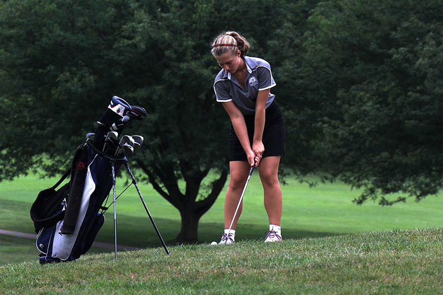 Concentrating on the ball and her form, junior Meg Green prepares to chip the ball onto the green.