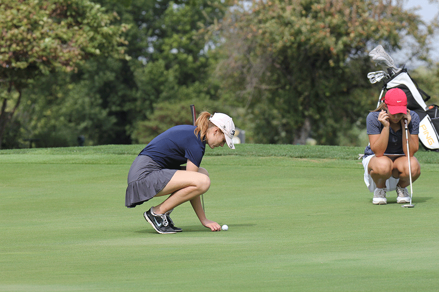On the green, junior Grace Van Inwegen marks her ball, so that it is out of the way.