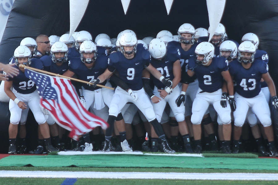 While waving an American flag, the Jaguar football team sways back and forth waiting for their entrance to start the game against Blue Valley Northwest in Friday, Sept. 11. The Jaguars defeated the Huskies, 40-6, furthering their record to 2-0.