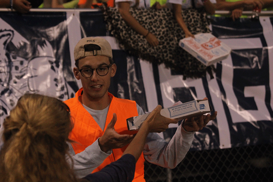 Junior Jack Campbell helps pass out pizzas to the student section during the football game against KC Southwest.