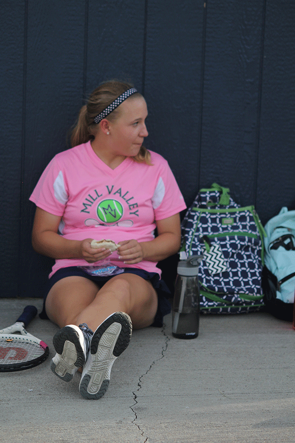 Eating a sandwich, sophomore Tori Wesp takes a break in the shade between matches. 