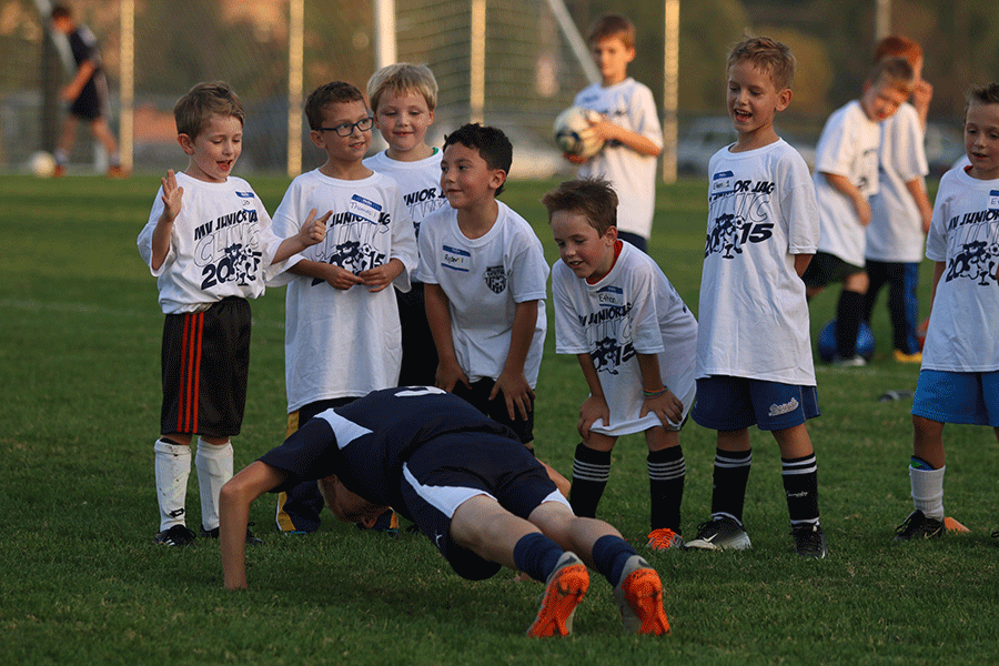 Children cheer on an older player demonstrating how to do a pushup.