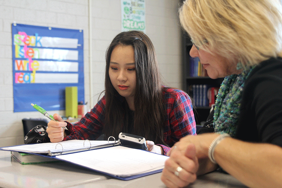 Junior Seohee Shin completes her homework with the aid of English For Speakers of Other Languages aide Melinda Lee. "Going to school in Kansas was confusing at first, but eventually I got used to it," Shin said.