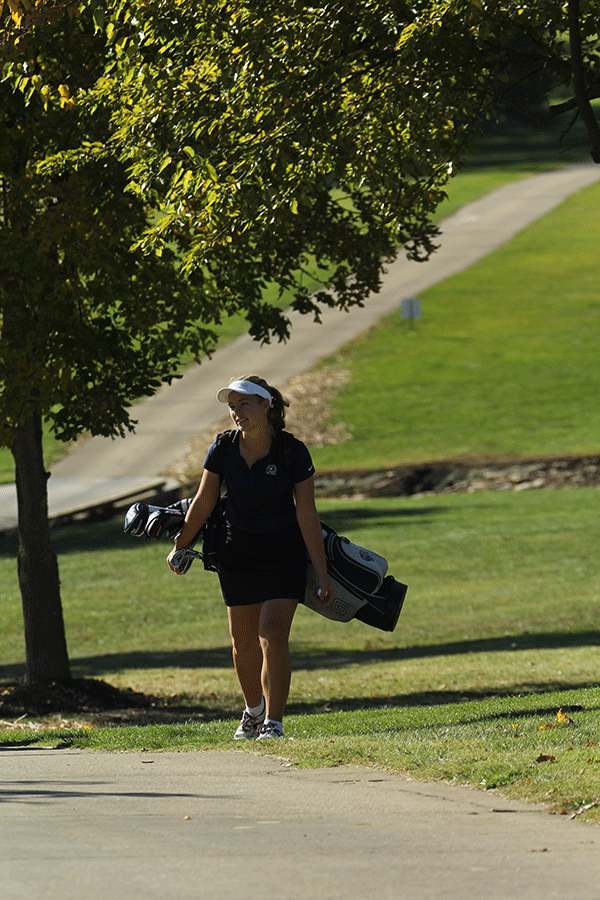 Junior Meg Green walks with her clubs and ball to hole number four.