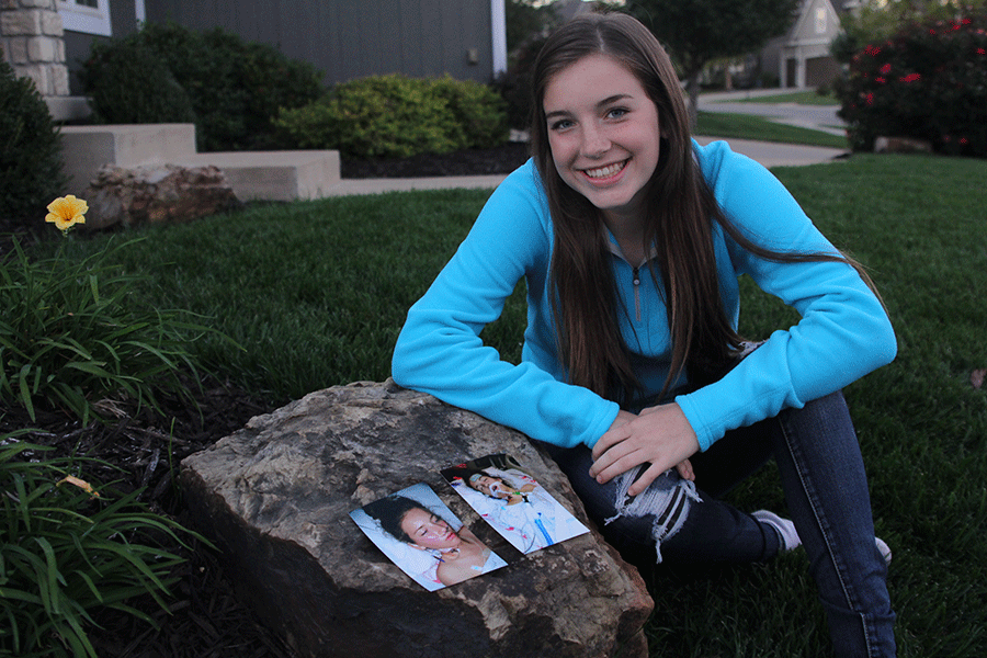 In memory of her open heart surgery, freshman Grace Lovett sits next to pictures of her in the hospital after her surgery last year.