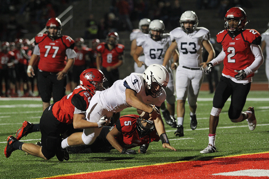 As he dives into the end zone for a touchdown, senior Logan Koch is tackled by a Lansing player at the away football game against Lansing High School on Friday, Oct. 9.