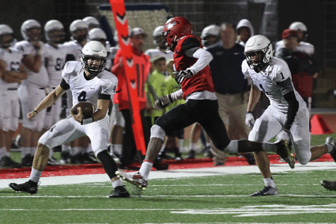 As senior Logan Koch runs the ball along the sidelines, senior Christian Jegen runs alongside in preparation to tackle the Lion defense. The Jaguars defeated the Lansing Lions 63-6 on Friday, Oct. 9.