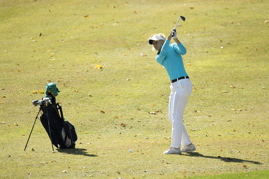 Taking some practice swings, junior Courtney Carlson prepares to chip the ball onto the green.