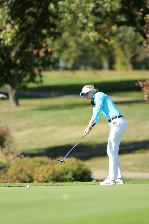 Putting the ball, junior Courtney Carlson battles the wind.